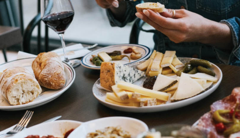 A table with a variety of foods and a person eating. Description generated by AI