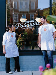 A man and woman standing in front of a store. Description generated by AI