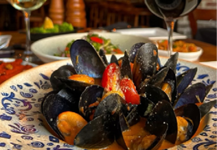 A plate of food with a wine glass and another wine glass on the table. Description generated by AI