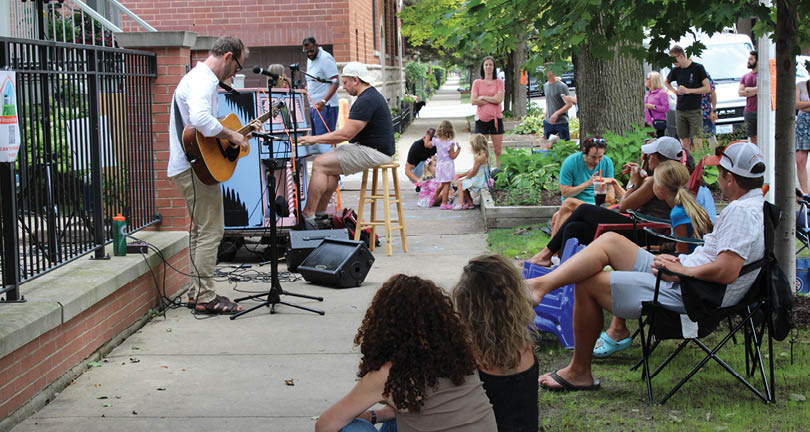 A man playing guitar on a sidewalk. Description generated by AI