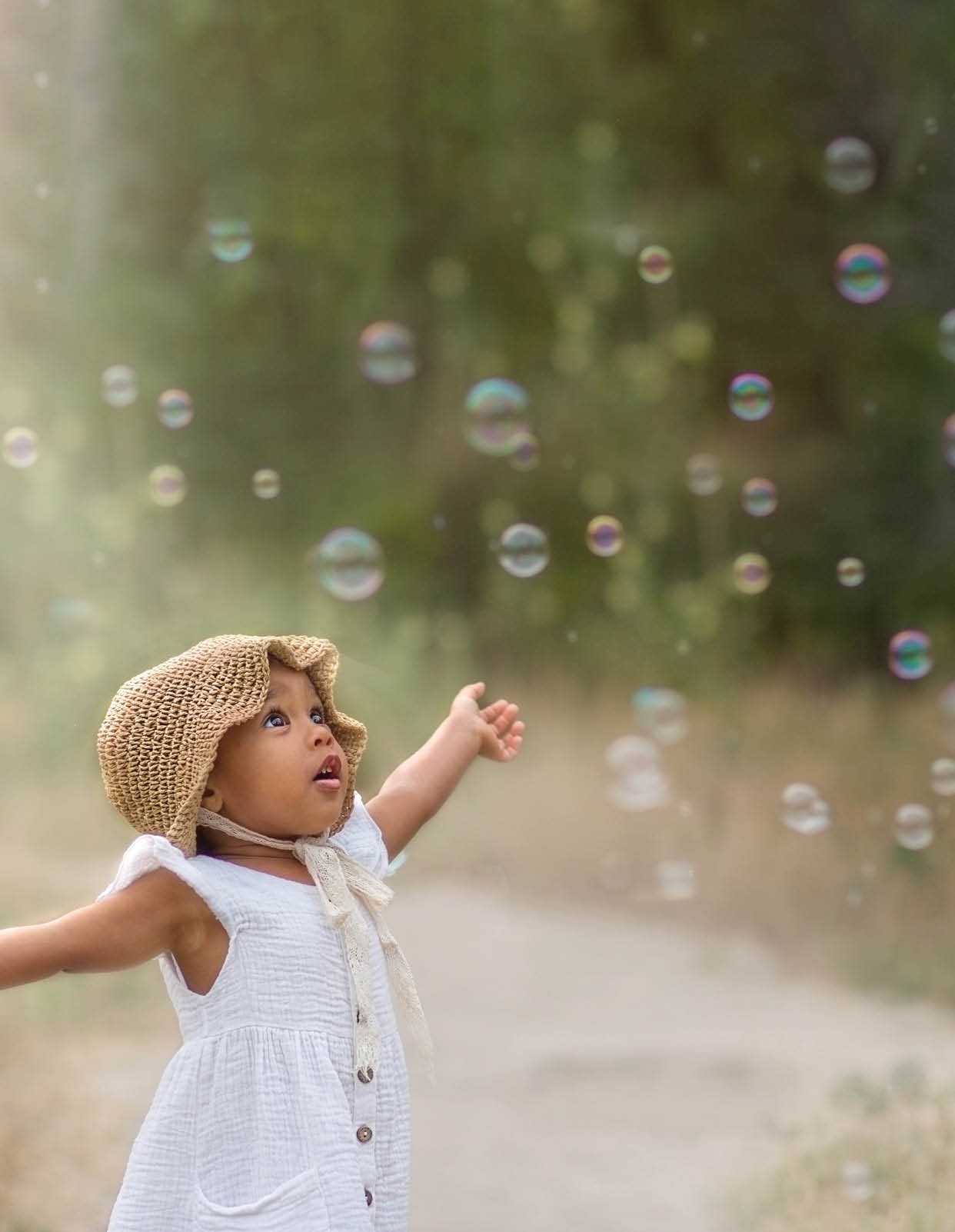 baby and soap bubbles. A little girl is waving her arms and trying to catch a lot of soap bubbles
