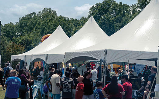 A large group of people are gathered under white tents. AI generated content