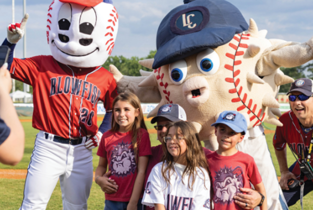 A group of children posing with a mascot and a baseball player. Description generated by AI