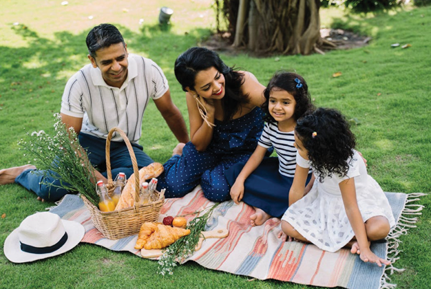 A family sitting on a blanket in a park. Description generated by AI