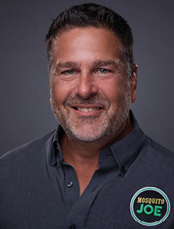 A man wearing a blue shirt with a logo on it. Description generated by AI