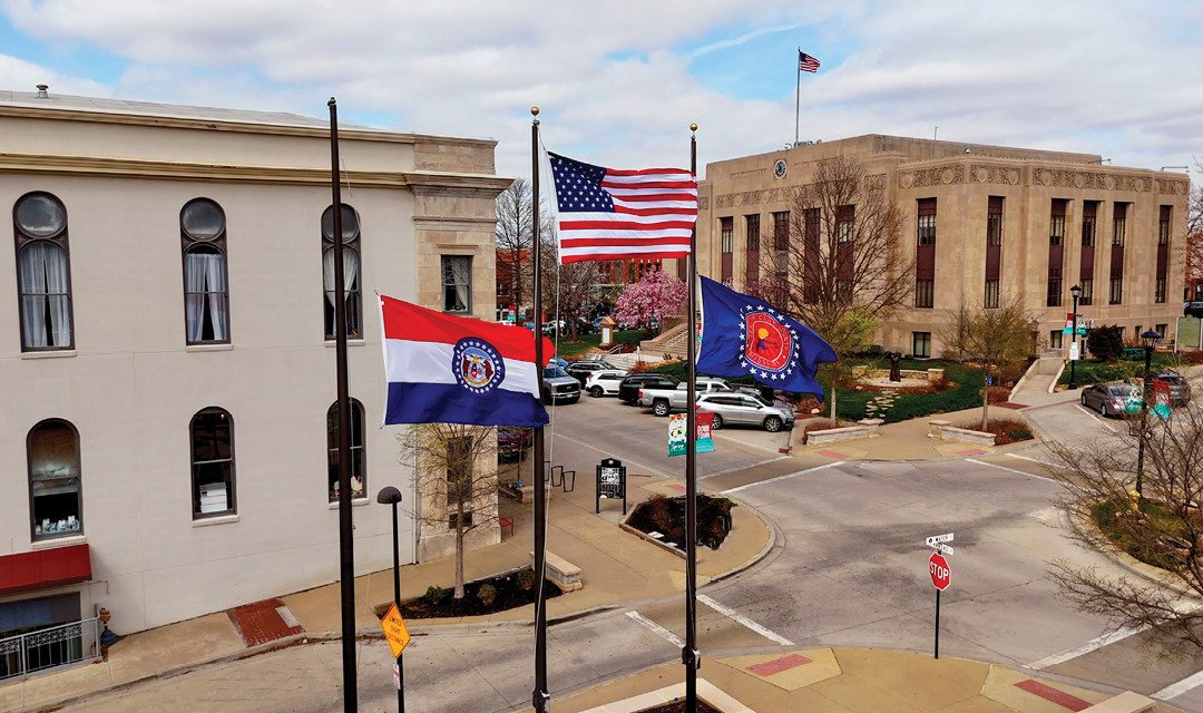 Two flags are flying on a street corner. Description generated by AI
