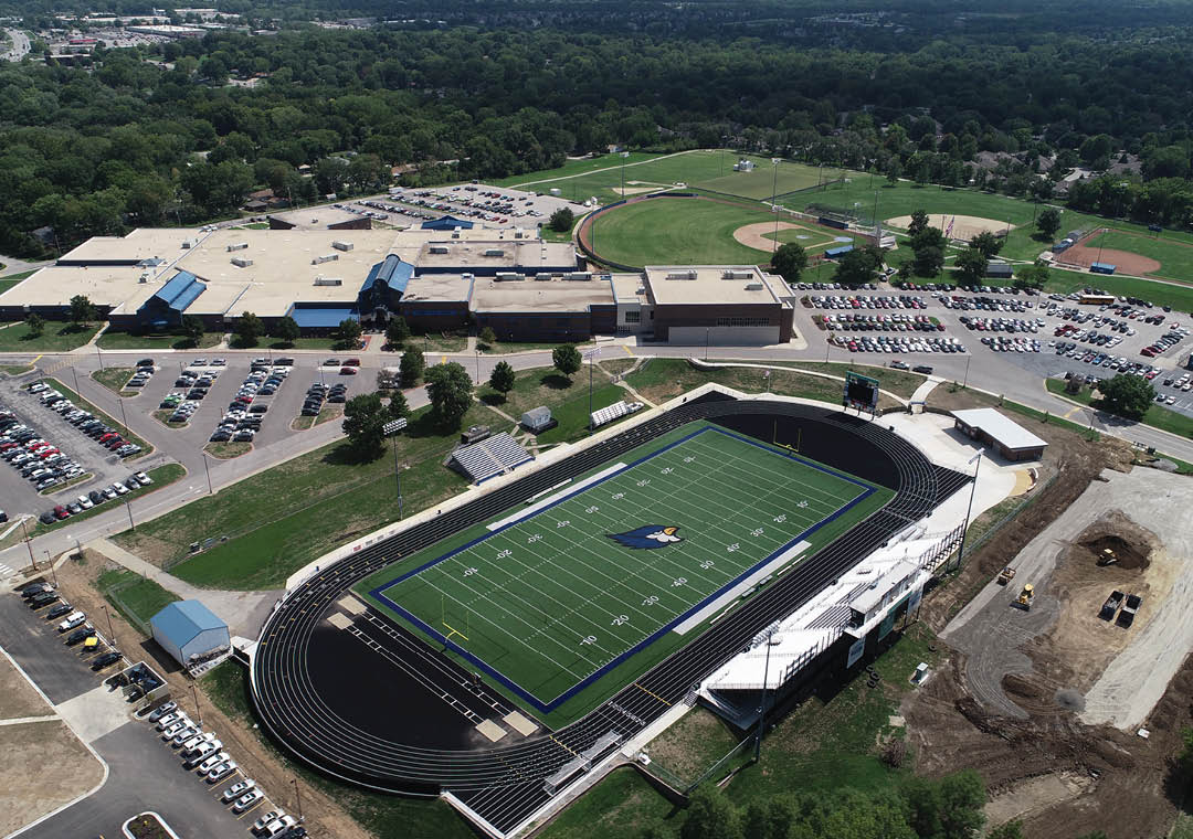 A football field with a blue field and a black and white stadium. Description generated by AI