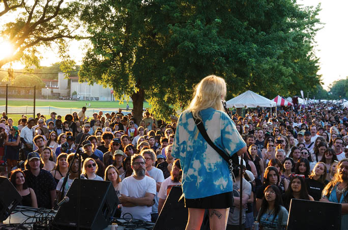 A woman is singing on stage in front of a crowd. Description generated by AI