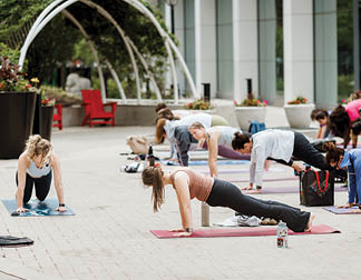 A group of people are doing yoga on a brick sidewalk. Description generated by AI