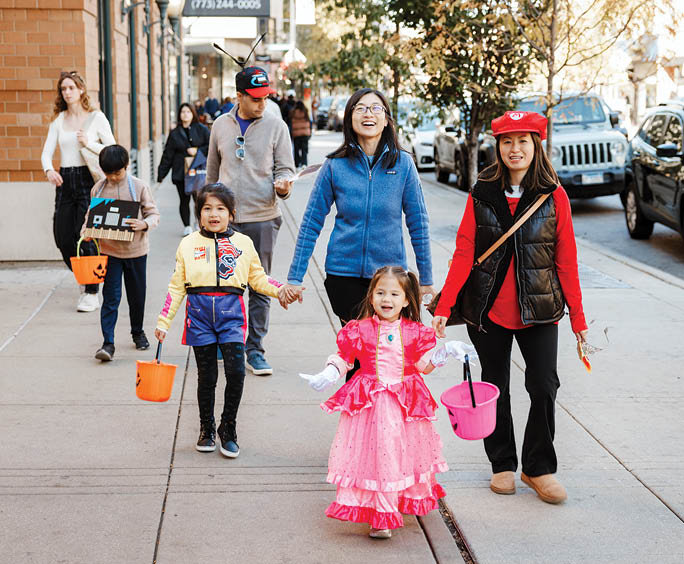 A group of people walking down a sidewalk. Description generated by AI