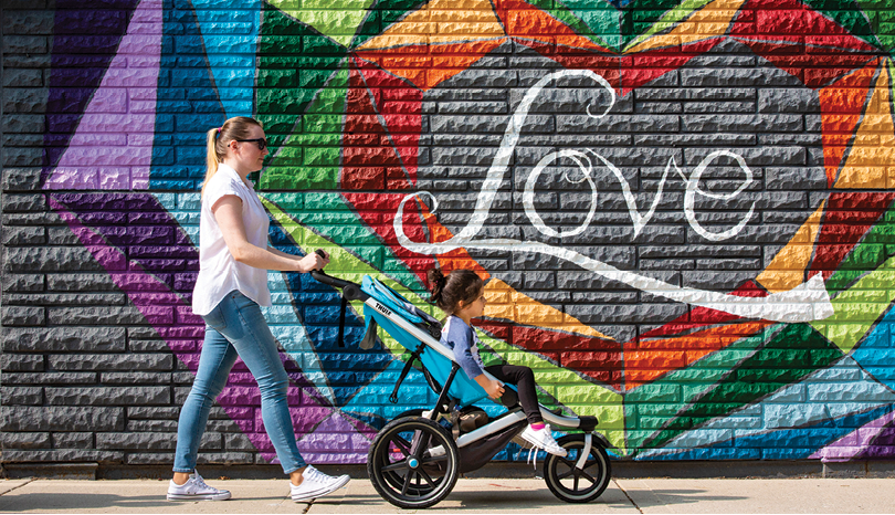 A woman pushing a stroller with a child in it. Description generated by AI