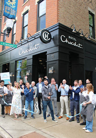 A group of people standing in front of a chocolate shop. Description generated by AI