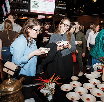 A group of people are standing around a table with plates of food. Description generated by AI