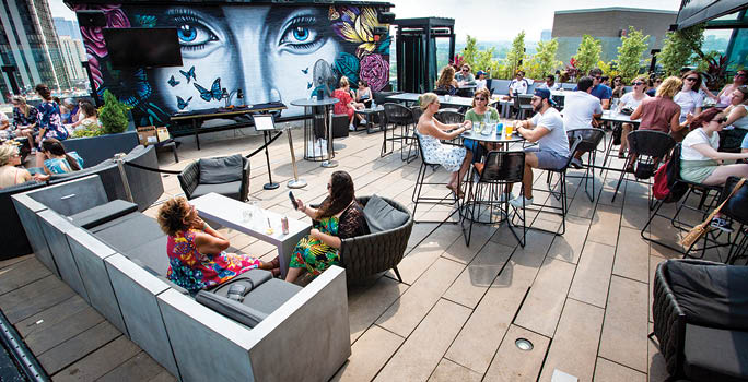 A group of people are sitting outside at tables. Description generated by AI
