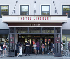 A group of people are standing outside of a hotel. Description generated by AI