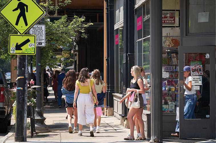 A group of people walking down a sidewalk. Description generated by AI