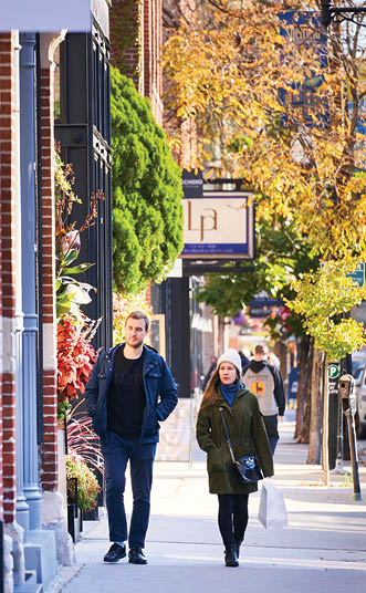 Two people walking down a sidewalk. Description generated by AI