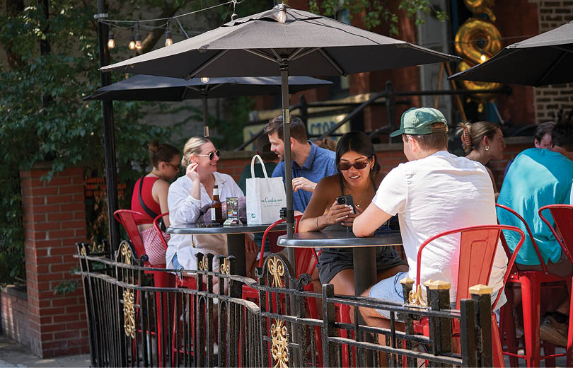 A group of people sitting at a table outside. Description generated by AI