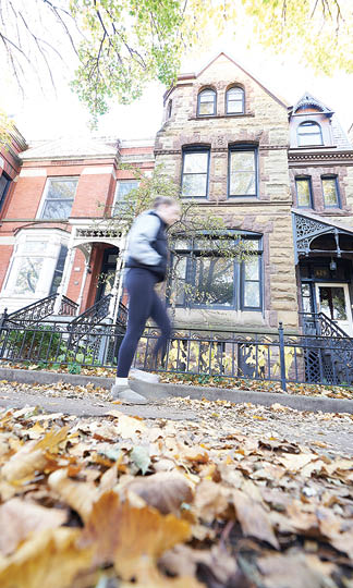 A woman walking on a sidewalk in front of a brick building. Description generated by AI