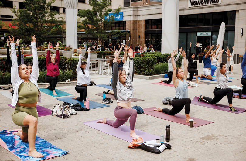 A group of people doing yoga on a sidewalk. Description generated by AI