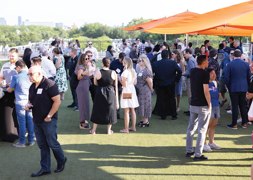 A large group of people are standing outside under a tent. Description generated by AI