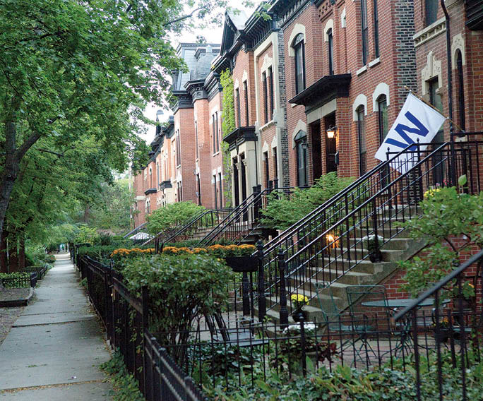 A tree-lined sidewalk with a black fence. Description generated by AI