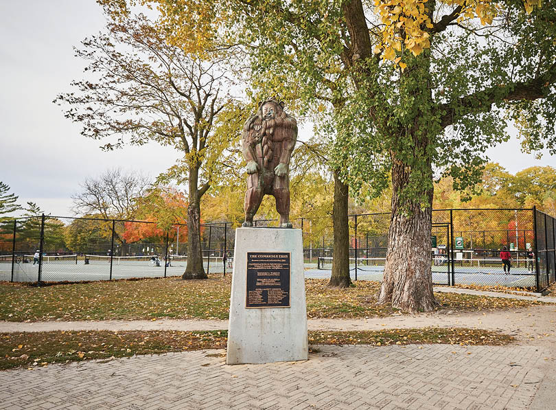 A statue of a man is on a pedestal in a park. Description generated by AI