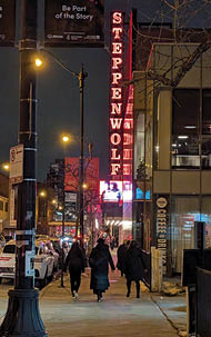A group of people walking on a sidewalk at night. Description generated by AI