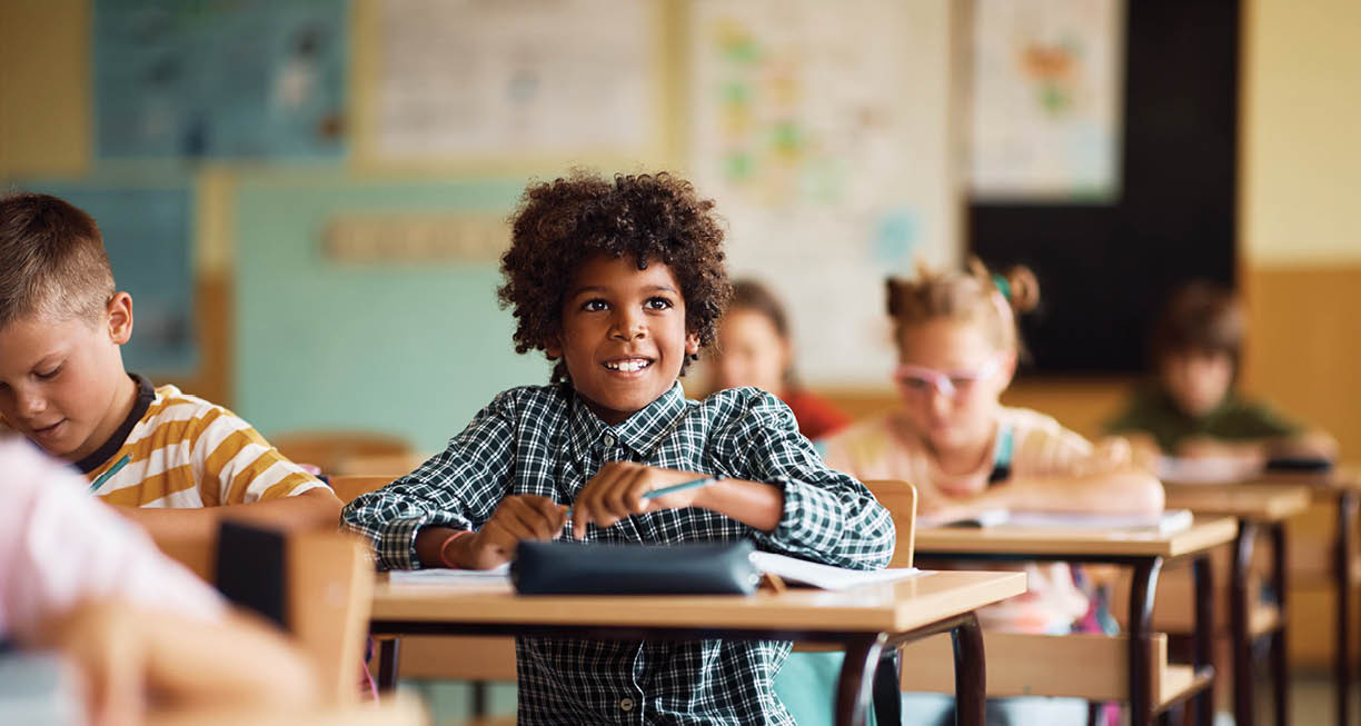 Happy African American elementary student and his classmates having a class at school. 