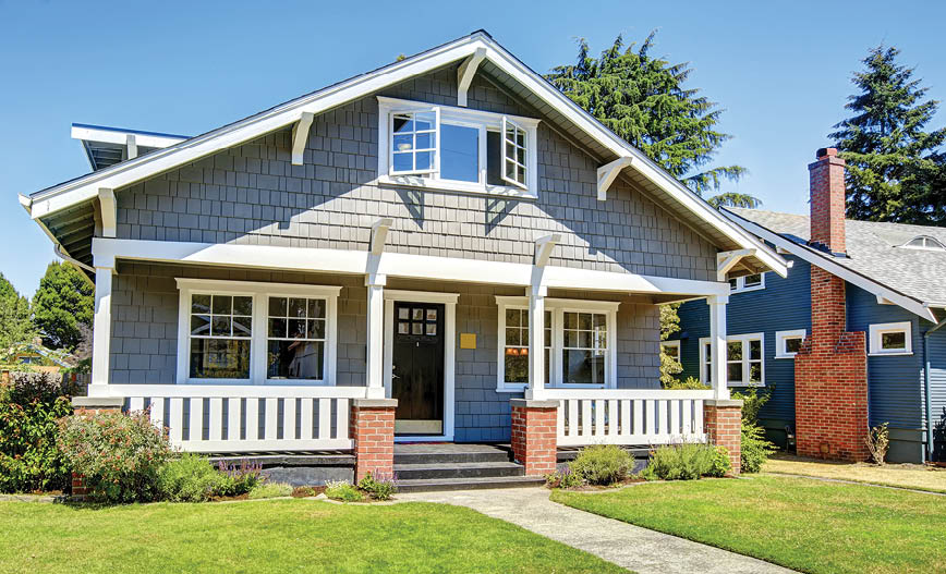 Clapboard siding house exterior. Large entance porch with brick trim and white railings