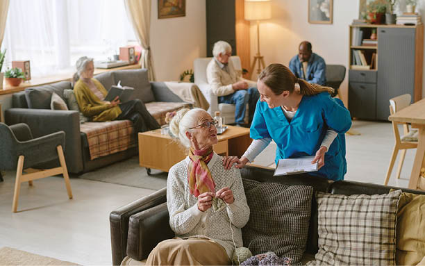 High angle shot of nurse communicating with senior woman who sharing progress in crocheting