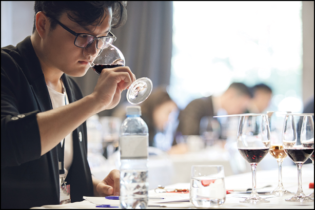 Asian appearance sommelier tasting red wine being smell being in blind tasting during pass training in wine school.
