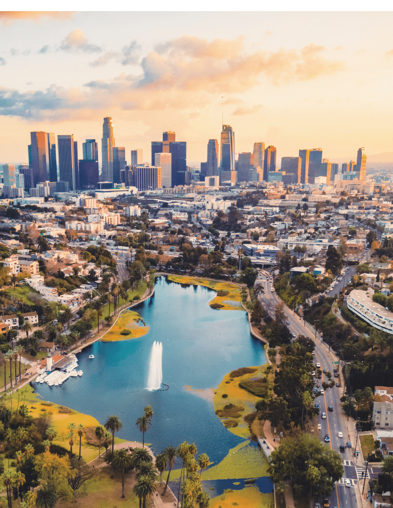 This is a drone photo taken from the above of the Echo Lake Park during sunset, showing the lake and the skyline of DTLA