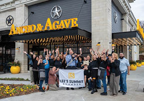 A group of people are standing outside of a restaurant, waving and smiling. AI generated content