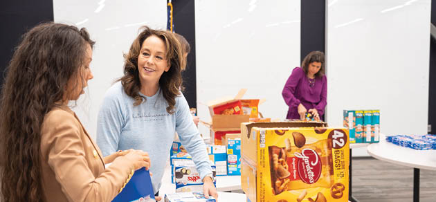Two women are standing in front of a table full of boxes of candy. AI generated content