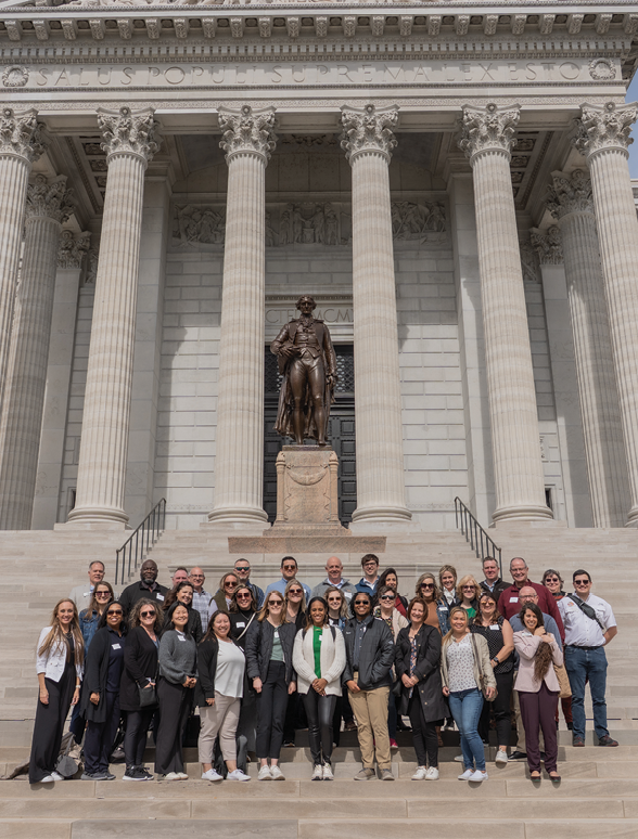 A group of people posing in front of a large building. AI generated content