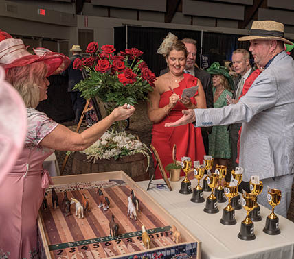 A group of people are gathered around a table with trophies and roses. A woman is handing a trophy to a man in a suit. AI generated content