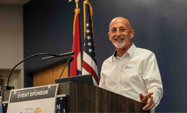 A man is giving a speech at a podium in front of an American flag. AI generated content