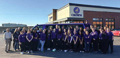 A group of people wearing purple shirts pose in front of a van. AI generated content