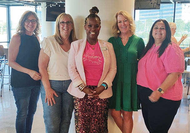 A group of women pose for a picture in a room. AI generated content