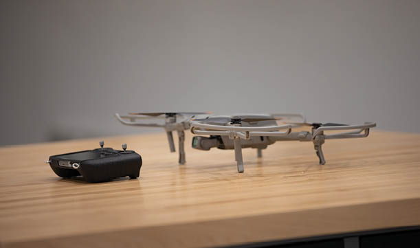 A drone is on a wooden table next to a remote control. AI generated content