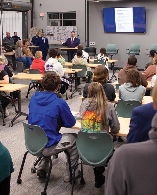 A large group of people are gathered in a room, sitting at tables and watching a presentation. AI generated content
