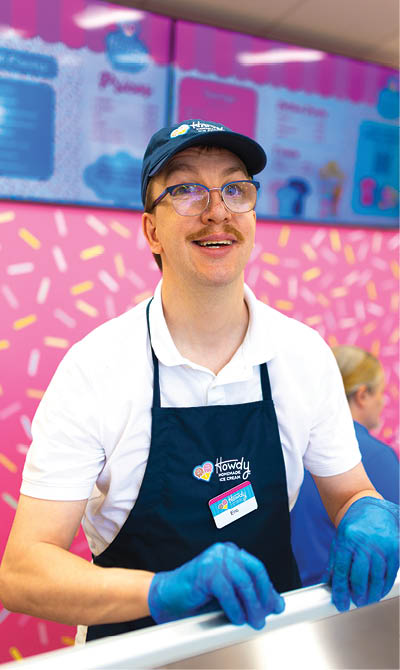 A man wearing a blue hat and a blue apron is smiling at the camera. AI generated content