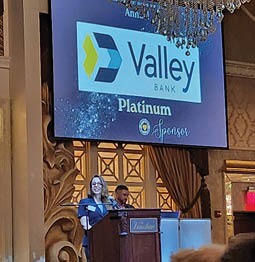 A woman is speaking at a podium in front of a large screen. AI generated content