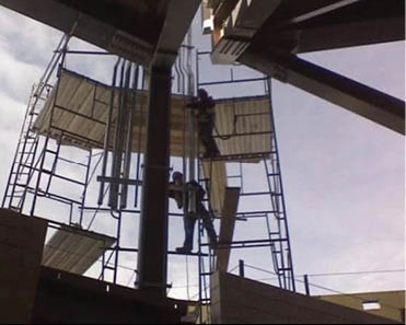 Two men are working on a construction site, one of them is on a ladder while the other is on a scaffolding. AI generated content