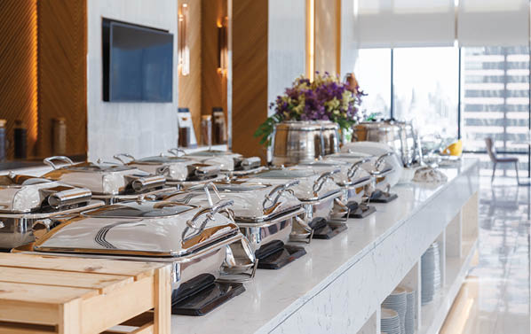 A buffet table with silverware and plates of food. AI generated content