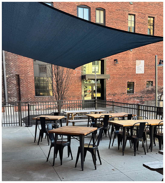 A patio with a blue canopy and a wooden table. Description generated by AI