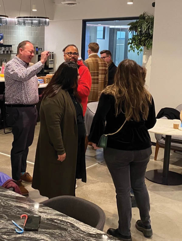 A group of people standing around a table. Description generated by AI
