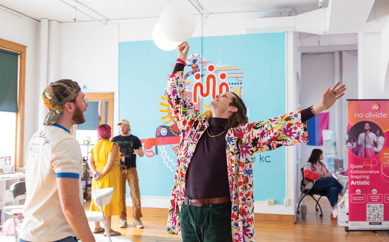 A man in a colorful jacket is reaching up to catch a balloon. Description generated by AI