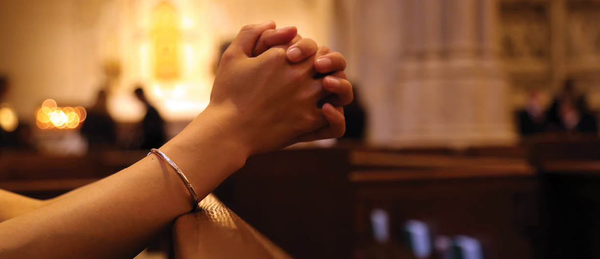 Closeup of woman's hands praying on church bench, coronavirus, copy space